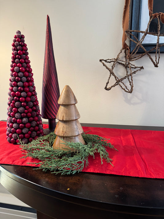 Decorative Christmas scene with trees, wreath, and star on a red tablecloth.