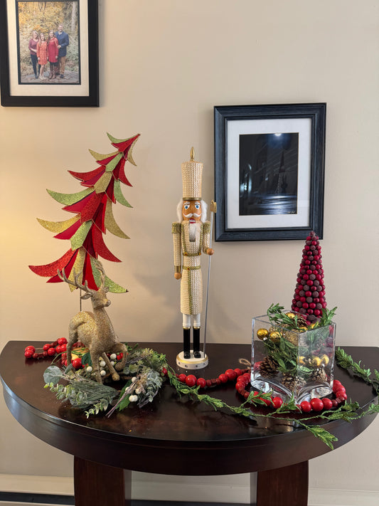 Decorative Christmas table setting with trees, nutcracker, and other ornaments on a wooden table.