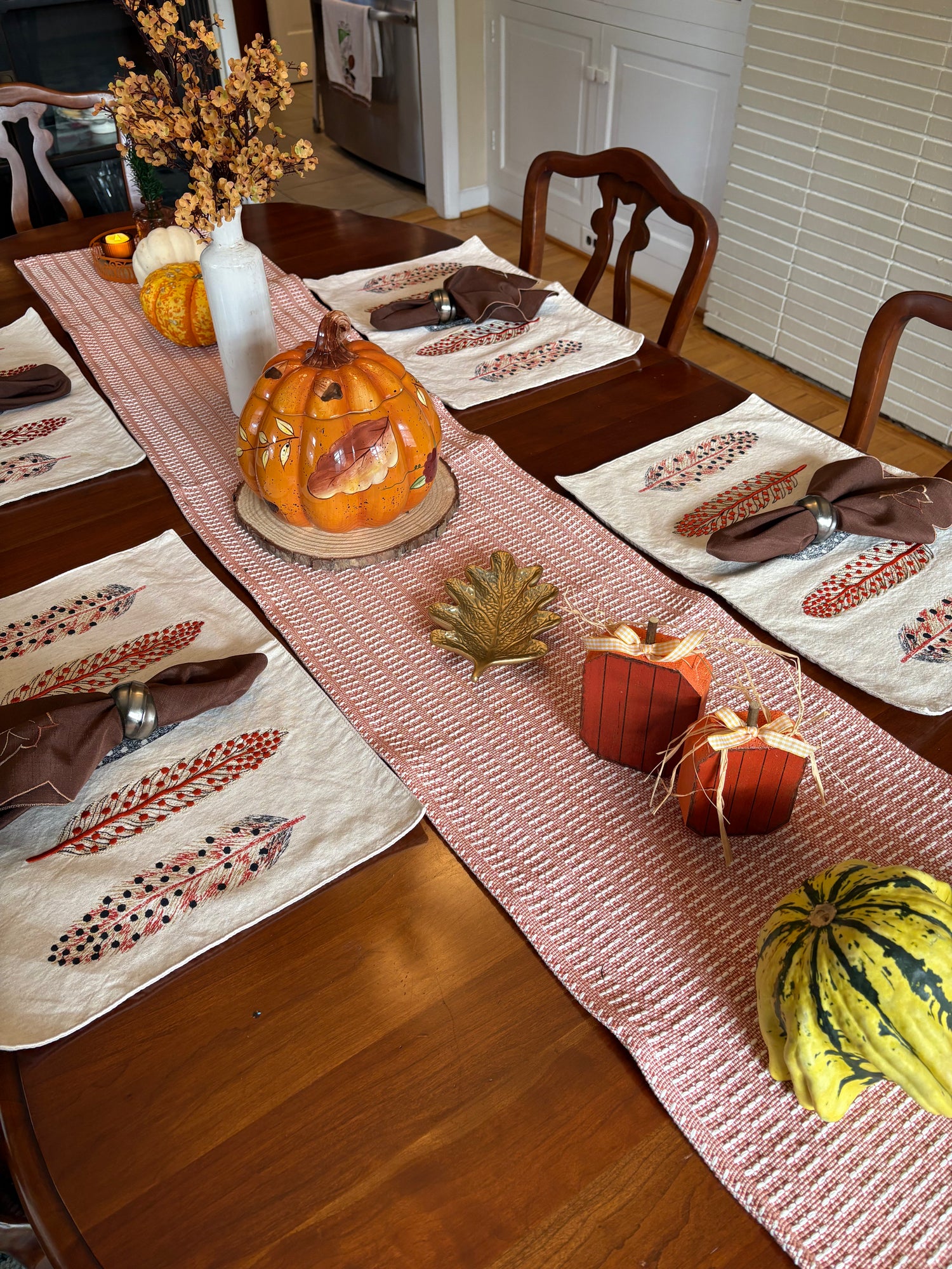 Dining table set with fall-themed decorations including pumpkins and place mats.