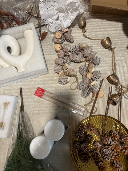 Decorative items including candles, pinecones, and a gold plate on a textured surface.